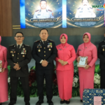 "Enam peserta acara, terdiri dari personel kepolisian dan anggota Bhayangkari, berpose bersama dalam acara seremonial resmi di dalam ruangan dengan logo Warta Edukasi di pojok kanan atas."